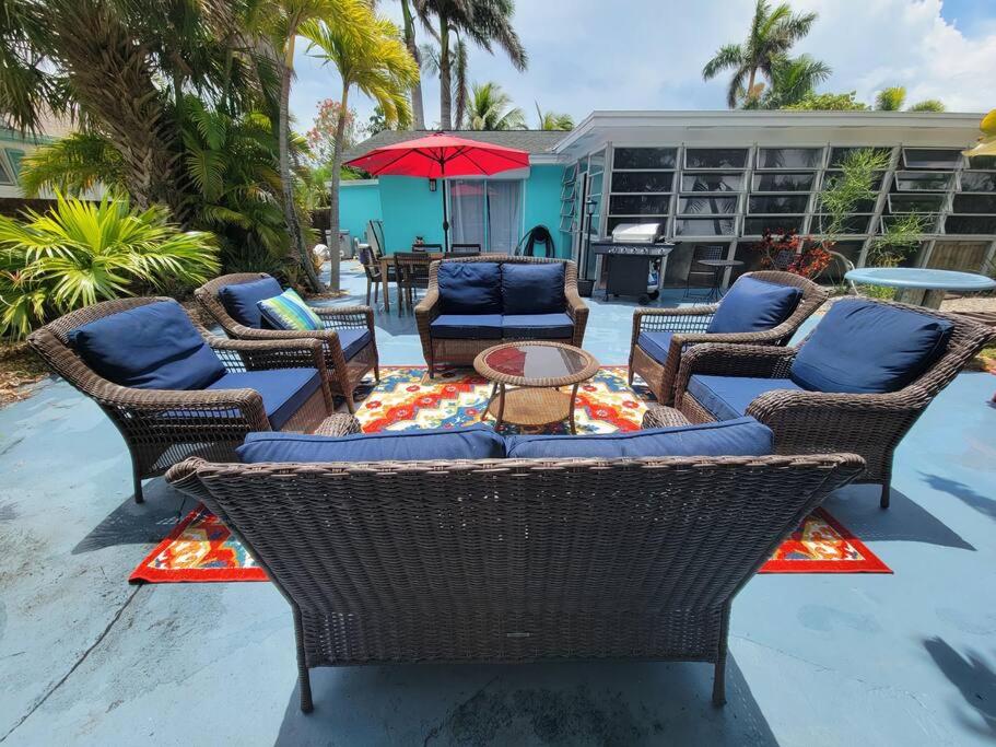 a patio with wicker chairs and a table with an umbrella at Beach & Surf Hacienda on Hutchinson Island in Fort Pierce