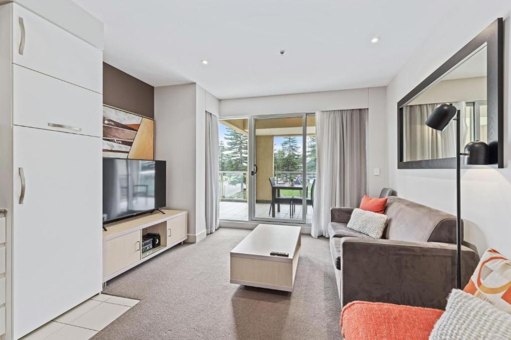 Una sala de estar con un sofá y un televisor. en Belle Escapes - Glenelg Shores Apartment, en Glenelg
