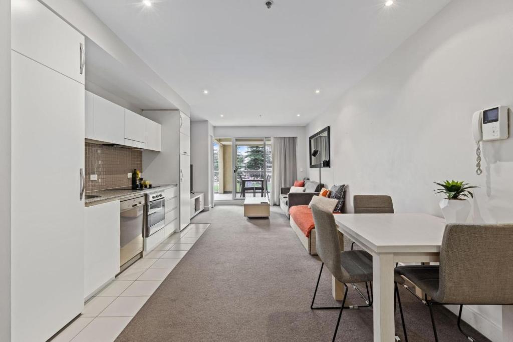 a kitchen and living room with a table and chairs at Belle Escapes - Glenelg Shores Apartment in Glenelg