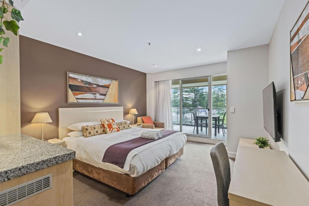 a bedroom with a king sized bed and a television at Belle Escapes - Glenelg Shores Studio in Glenelg