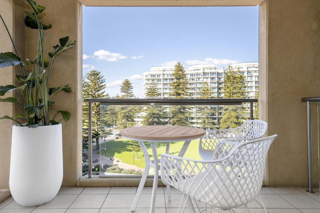 a balcony with a table and chairs in front of a window at Belle Escapes - Park View Family Stay at the Pier in Glenelg