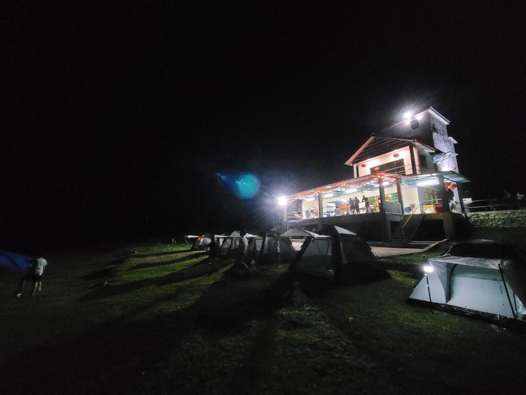 a house lit up at night with a green light at Lipis Riverfront Resort in Kuala Lipis