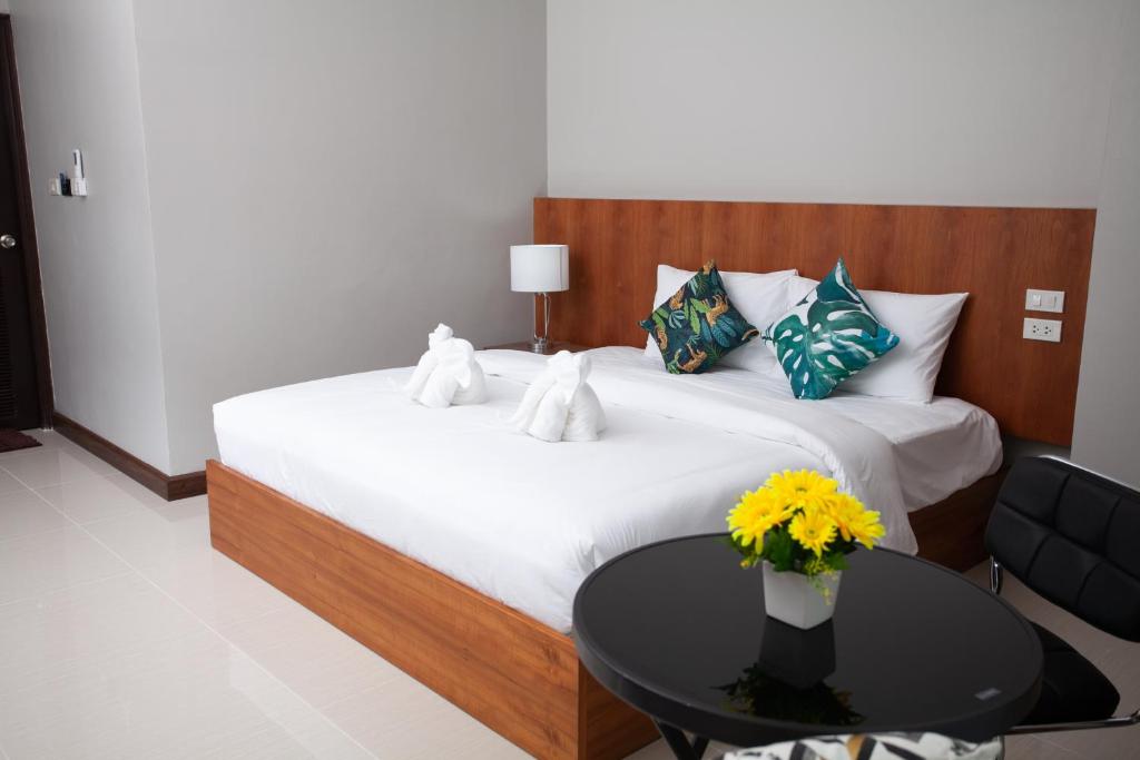 - une chambre avec un lit et une table ornée d'un vase de fleurs dans l'établissement The Brown Boutique Patong, à Patong Beach
