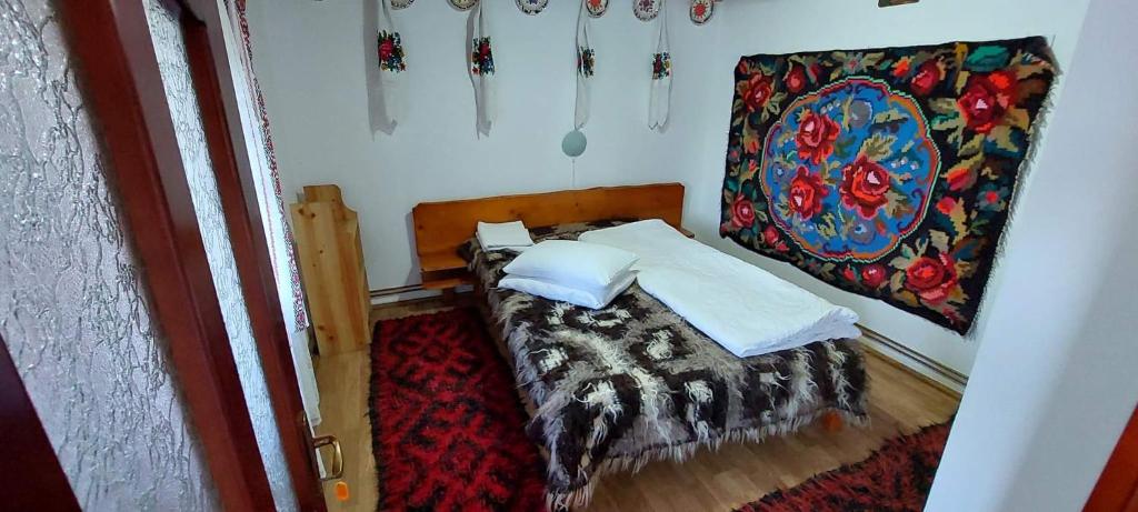niewielka sypialnia z łóżkiem i obrazem na ścianie w obiekcie Pensiunea La Gorgan w mieście Vadu Izei