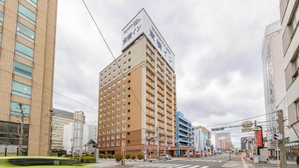 a tall building with a sign on top of it at Toyoko Inn Oita Ekimae in Oita