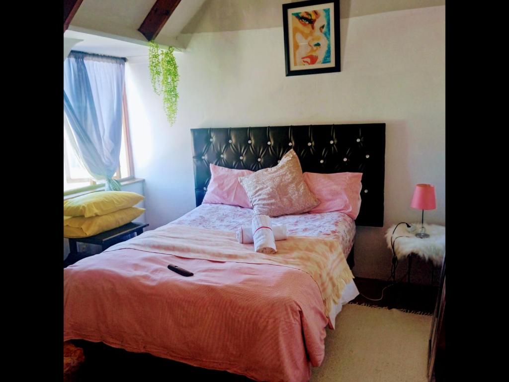 een slaapkamer met een groot bed met roze lakens bij Zagorski bed and breakfast in Kaapstad