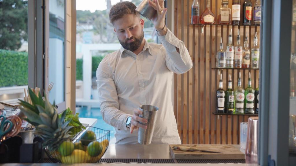 a man standing at a counter in a bar at Hôtel Beau Soleil in Le Lavandou