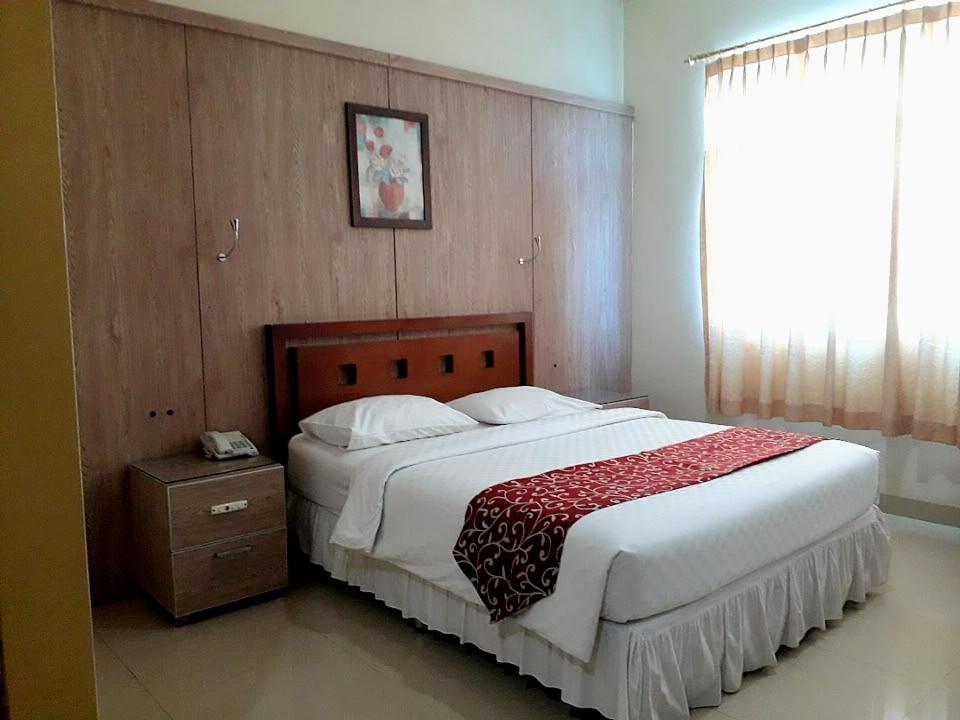 a bedroom with a large bed with a red and white blanket at THE IGNISLO HOTEL SORONG in Sorong