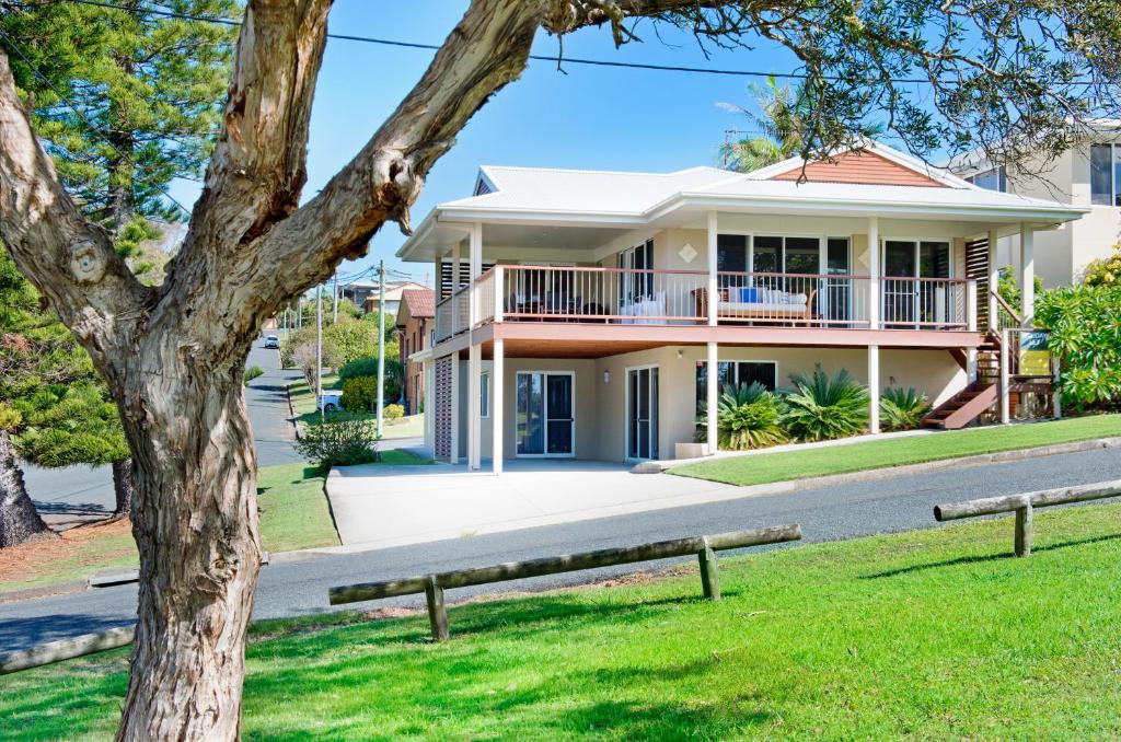 a house with a tree in front of it at Allure By The Sea in Bonny Hills