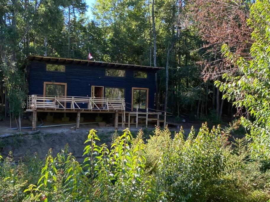 a blue cabin in the woods with a deck at Casa en Futrono - Llifén-Ranco (tinaja adicional) in Futrono