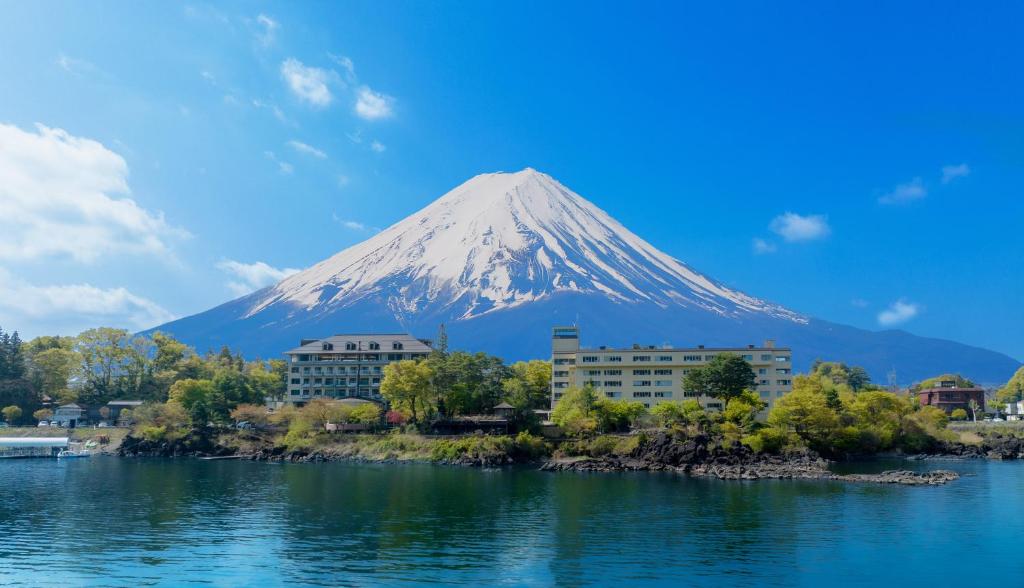 a mountain in front of a city and a body of water at Fuji Lake Hotel in Fujikawaguchiko