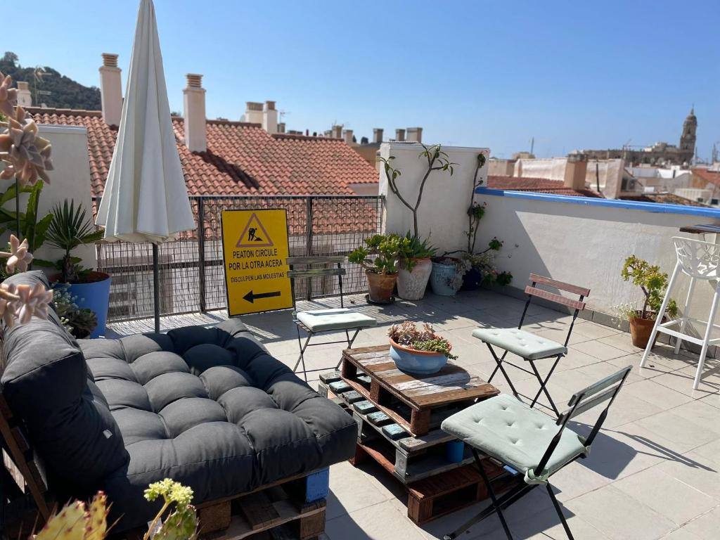 a patio with a couch and chairs and an umbrella at Charming home with private terrace,heart of Málaga in Málaga