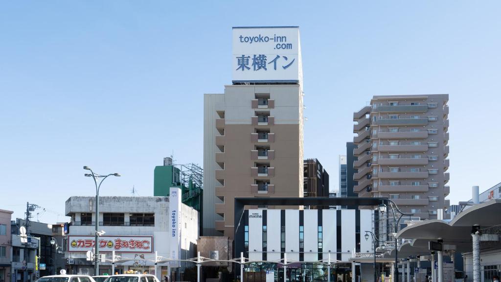 a tall building with a sign on it in a city at Toyoko Inn Shizuoka Fujieda eki Kita guchi in Fujieda