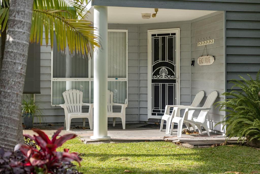 a porch with white chairs on a house at Pacific Palms in Elizabeth Beach