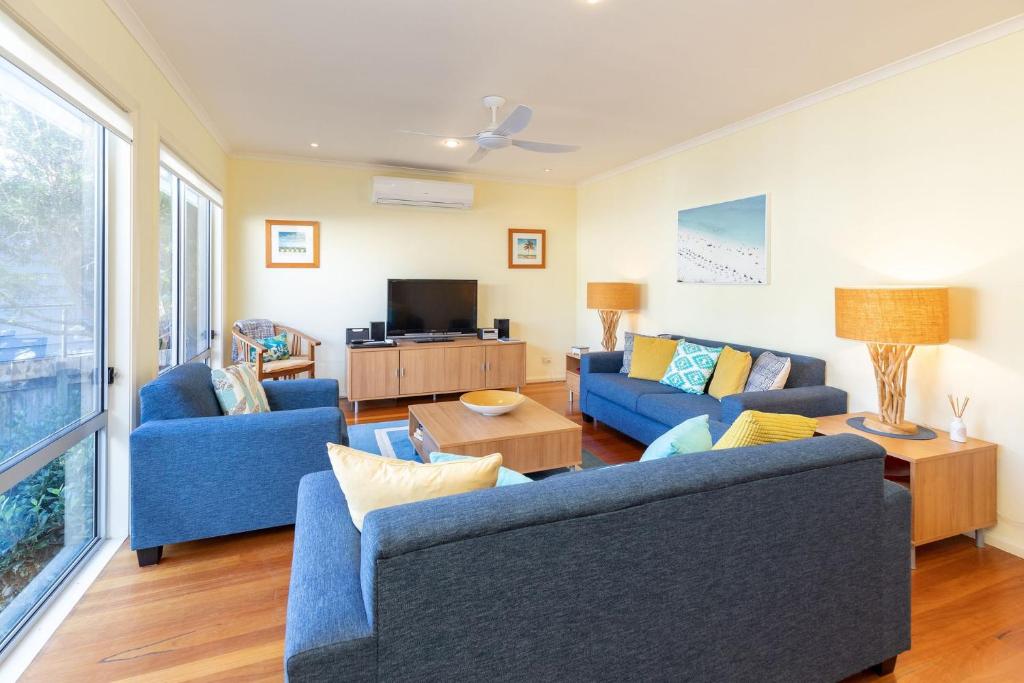 a living room with two blue couches and a tv at Point Break in Boomerang Beach