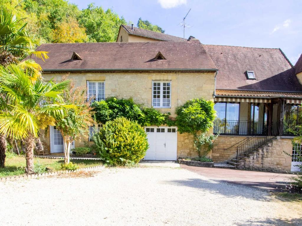 una gran casa de ladrillo con garaje blanco en Gîte La Roque-Gageac, 4 pièces, 5 personnes - FR-1-616-278, en La Roque-Gageac