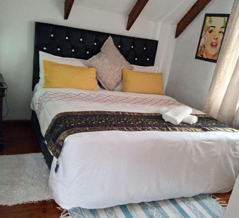 1 dormitorio con 1 cama blanca grande con almohadas amarillas en Room in BB - Zagorskis Bed and breakfast close to the beach and commodities, en Ciudad del Cabo