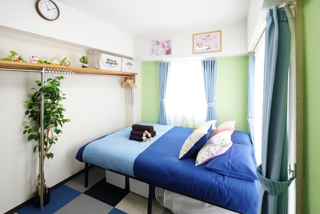 een slaapkamer met een blauw bed en een raam bij Kameari 1111 Budget Stay High Floor Near Station Mall Disney Access in Tokyo