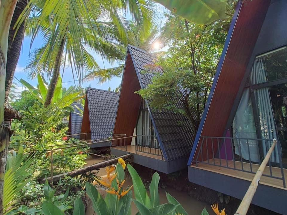 une maison avec un balcon et quelques arbres et plantes dans l'établissement Homestay Nam Hàm Luông, à Ben Tre