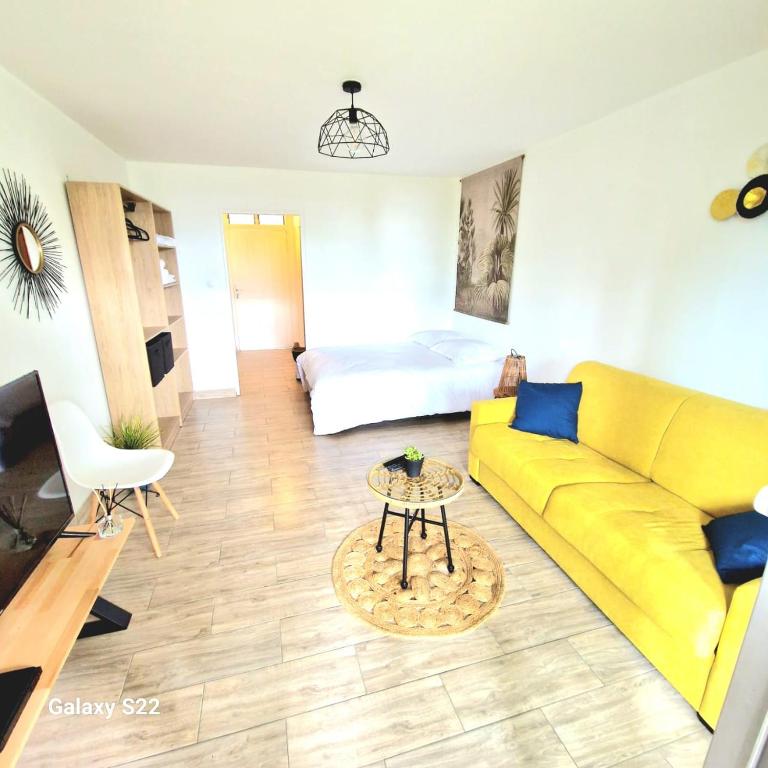 un soggiorno con un divano giallo e un letto di Studio P'ti Boucan a Saint-Gilles-les Bains