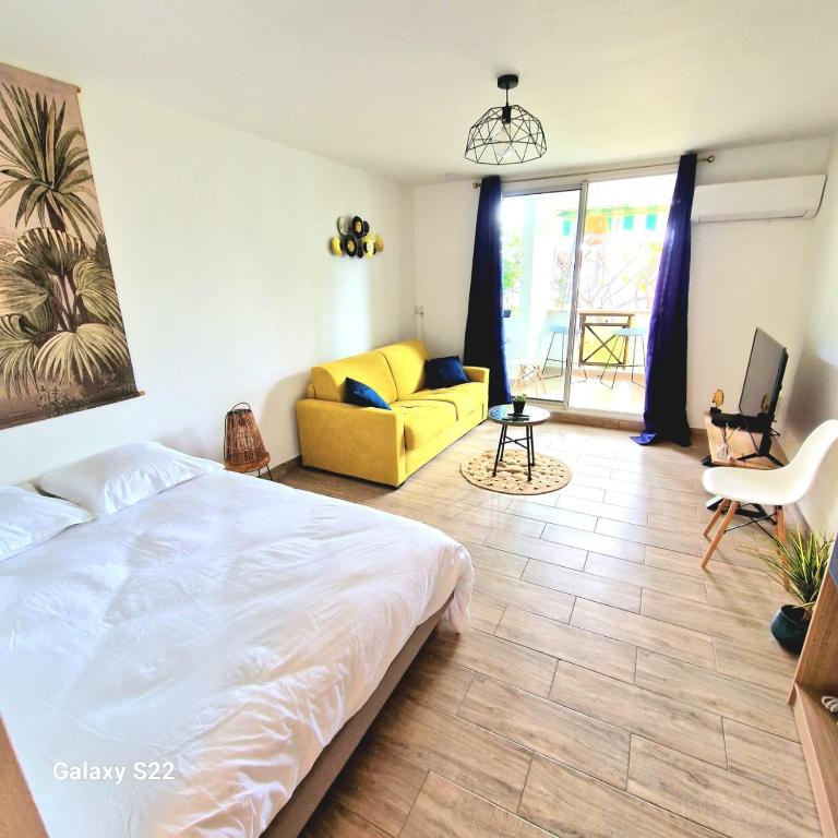 1 dormitorio con cama y sofá amarillo en Studio P'ti Boucan, en Saint-Gilles-les-Bains