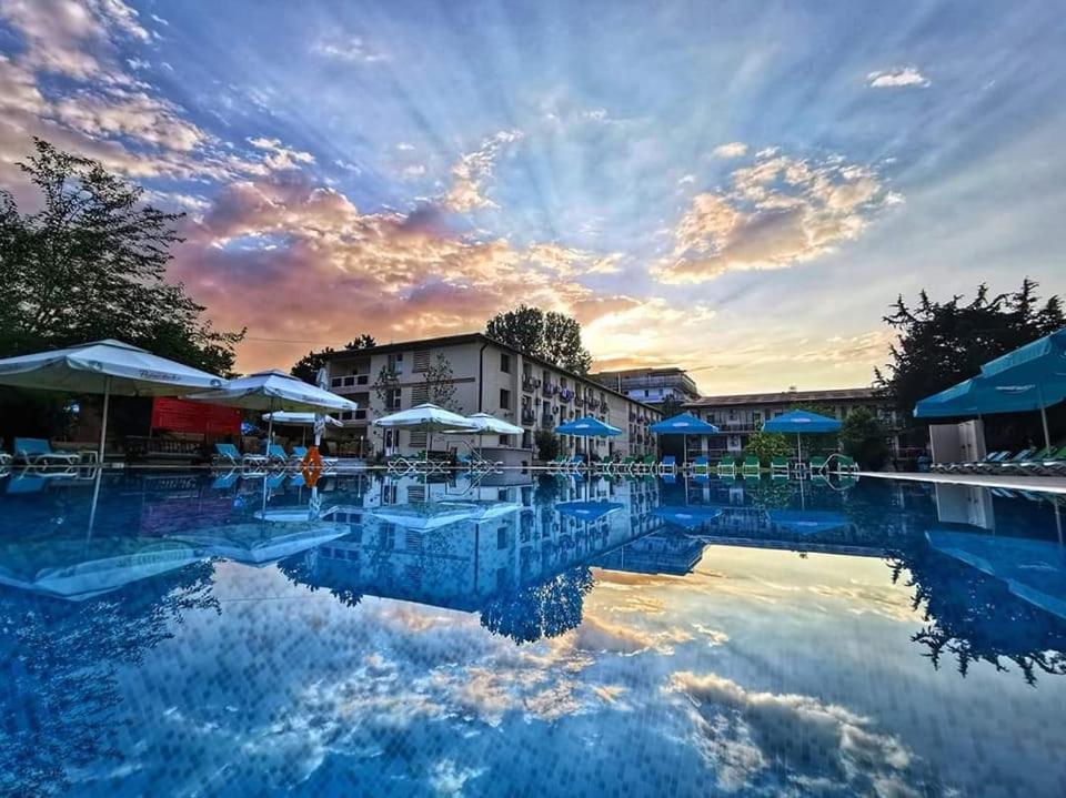 a large swimming pool with tables and umbrellas at Q Hotel in Neptun