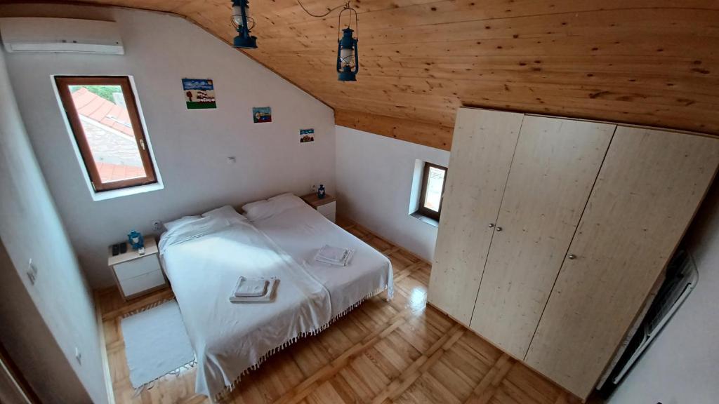 Schlafzimmer mit einem weißen Bett und Holzdecken in der Unterkunft Apartmani Krapanj in Krapanj