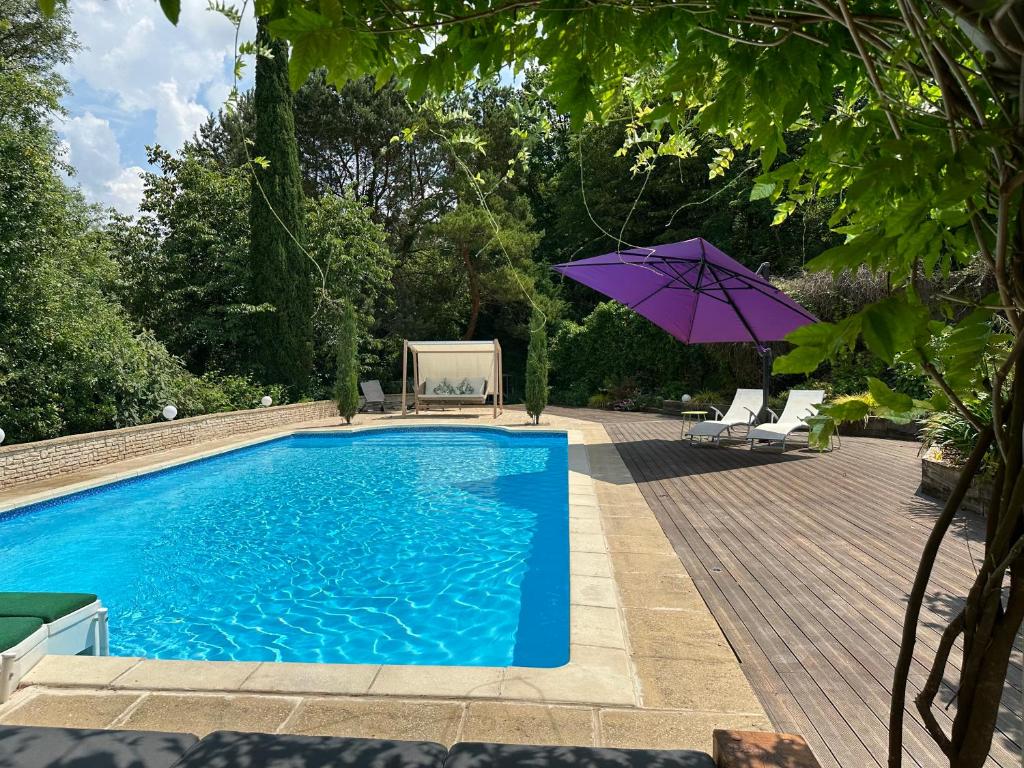 una piscina con sombrilla y sillas moradas en Gîte Le Dolmen, Cognac, en Julienne