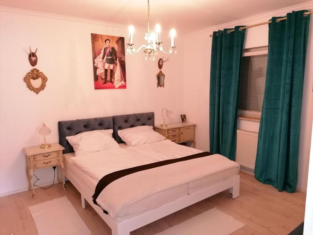 een slaapkamer met een bed met groene gordijnen en een kroonluchter bij Ferienwohnung Helli in Teisendorf