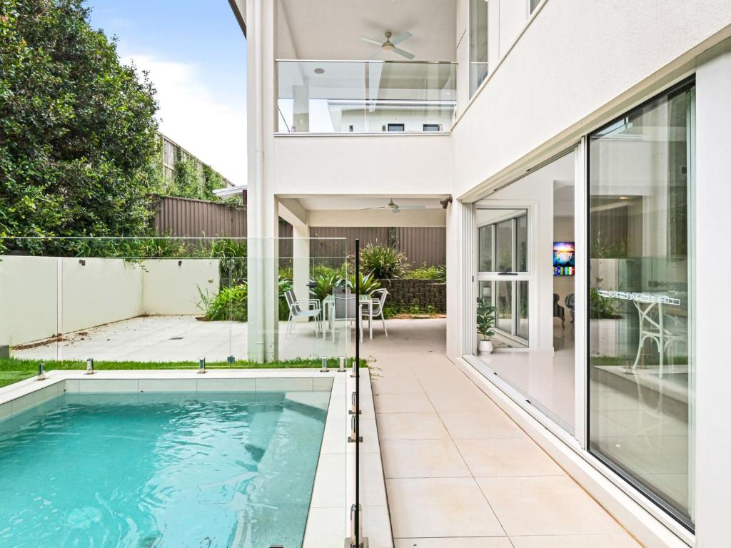 an indoor swimming pool in a house with glass doors at Luxury Hilltop Brand-New 5BD Holiday Home in Brisbane
