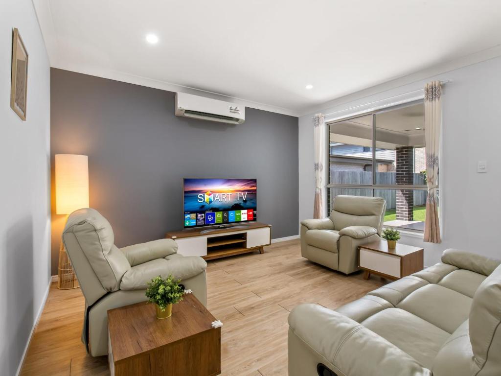 a living room with couches and a flat screen tv at Spacious Newly Furnished 4BD Family Retreat in Doolandella