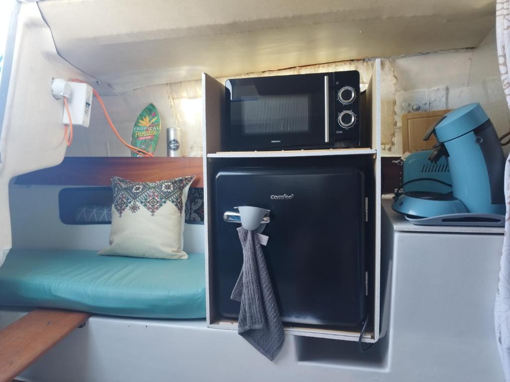 a microwave and a chair in a tiny house at Bateau port Cap d'Agde in Cap d'Agde