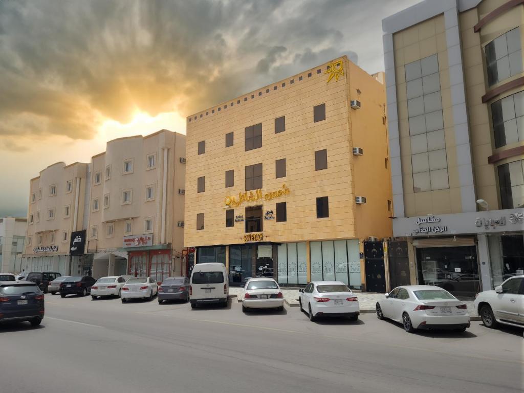 un grupo de coches estacionados frente a un edificio en Shams Alshate شمس الشاطئ en Buraidah