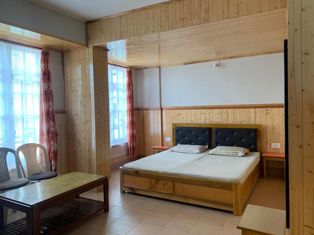 1 dormitorio con cama, mesa y ventanas en Hotel Palbheu Inn, en Namchi