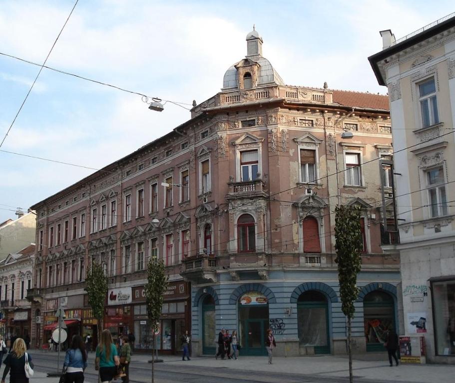 un grand bâtiment dans une rue où les gens marchent devant dans l'établissement Kriston Apartman 2, à Miskolc