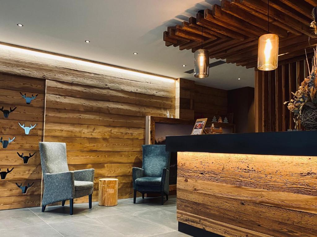 a lobby with two chairs and wooden walls at Edelweiss Alpine Nature in Pinzolo