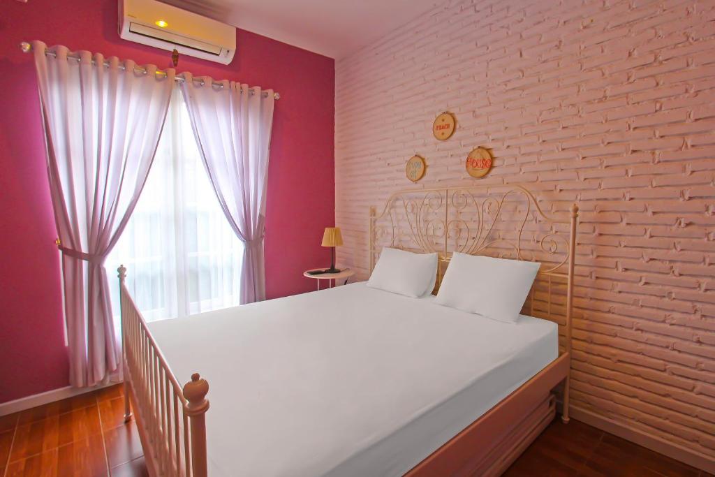 a bedroom with a white bed and a brick wall at Capital O 92559 Sweet Peach House in Senggigi