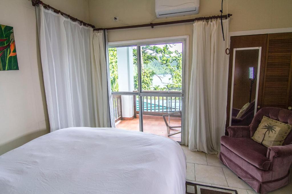 a bedroom with a bed and a chair and a balcony at The Dudek's Nest B&B in Ngermid
