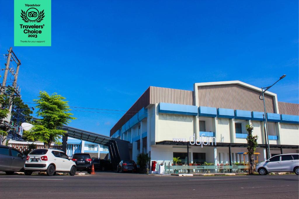 un estacionamiento con autos estacionados frente a un edificio en Dafam Hotel Cilacap, en Cilacap