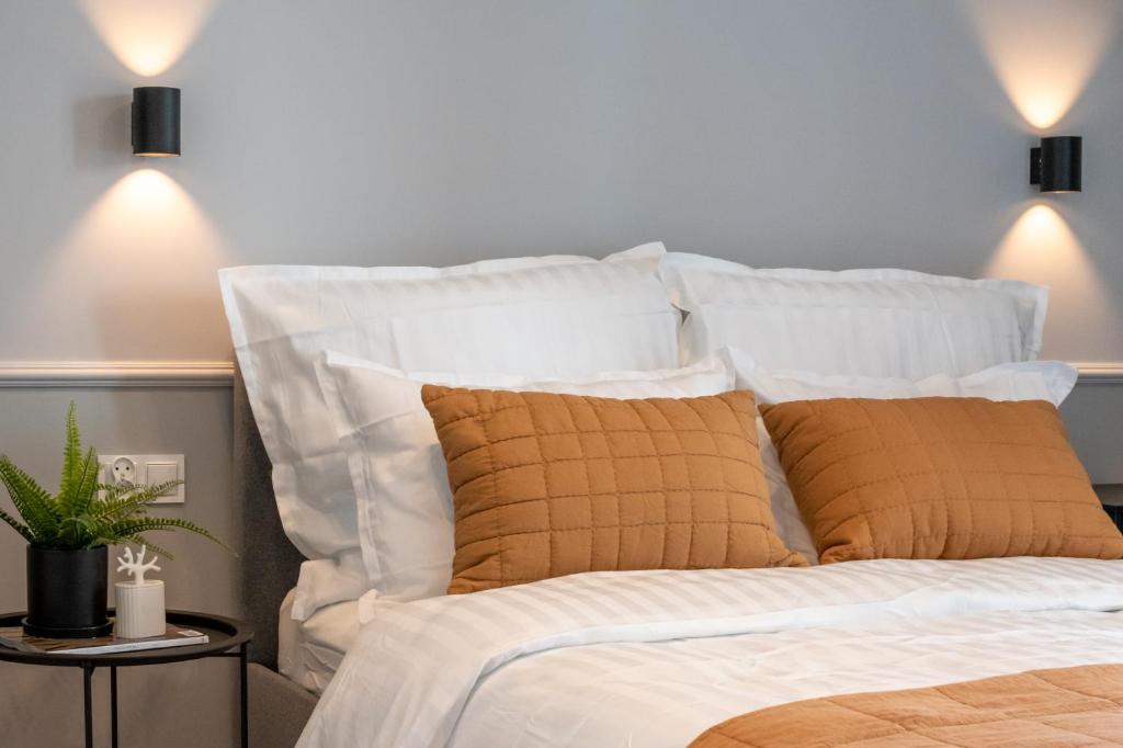 1 cama con sábanas blancas y almohadas de color naranja en A Morze Las - apartament na Wyspie Sobieszewskiej en Gdansk