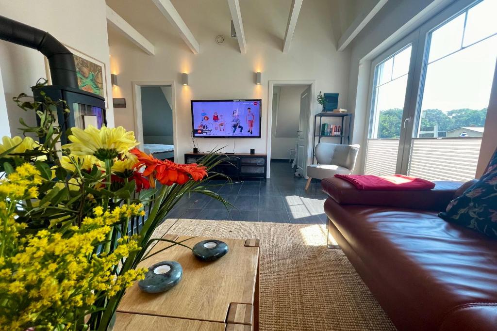a living room with a couch and a table with flowers at Ferienwohnung4 im Haus Möwe in Thiessow