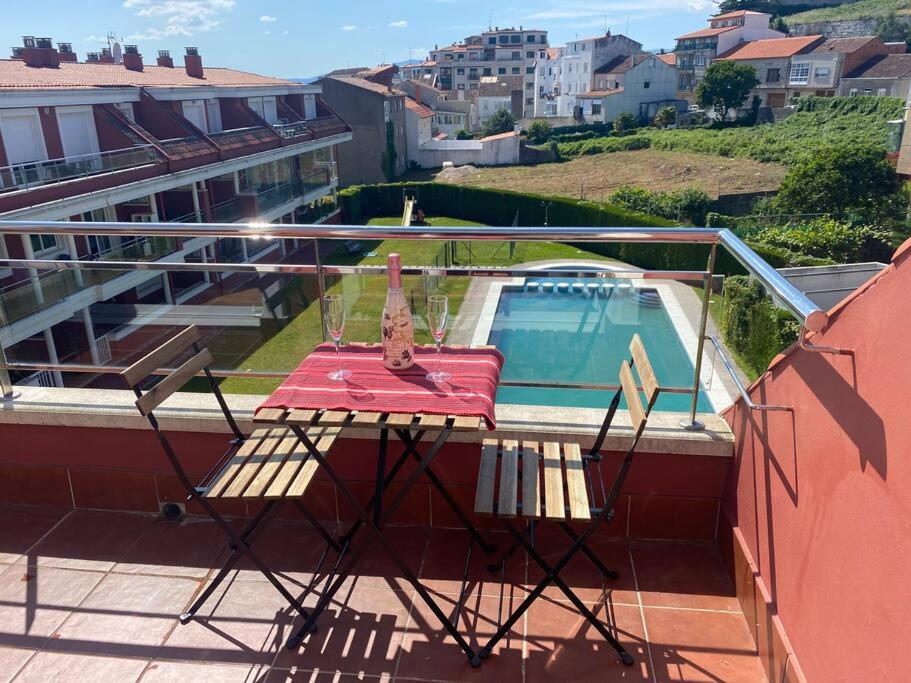 uma mesa e cadeiras numa varanda com piscina em Ático con terraza, piscina y gimnasio em Vilagarcía de Arousa