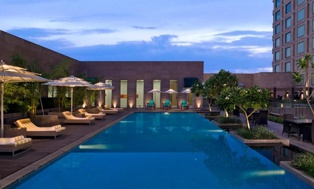 a swimming pool with chairs and umbrellas at a hotel at Radisson Blu Hotel Amritsar in Amritsar