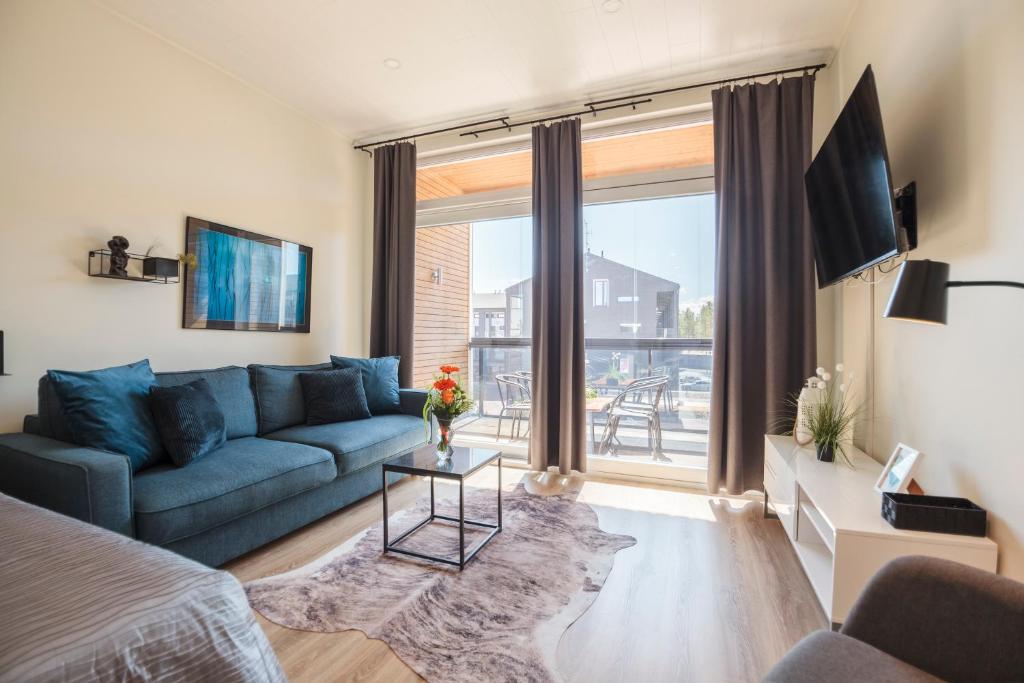 uma sala de estar com um sofá azul e uma grande janela em Apartment Aurinkoranta D8 saunallinen yksiö Kalajoki em Kalajoki