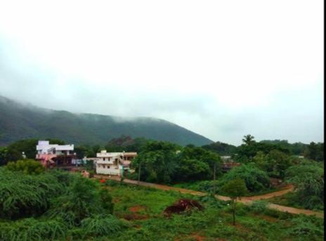 Duplex house homestay near Vijayawada, Tadepalli في فيجاياوادا: اطلاله على جبل به بيوت واشجار
