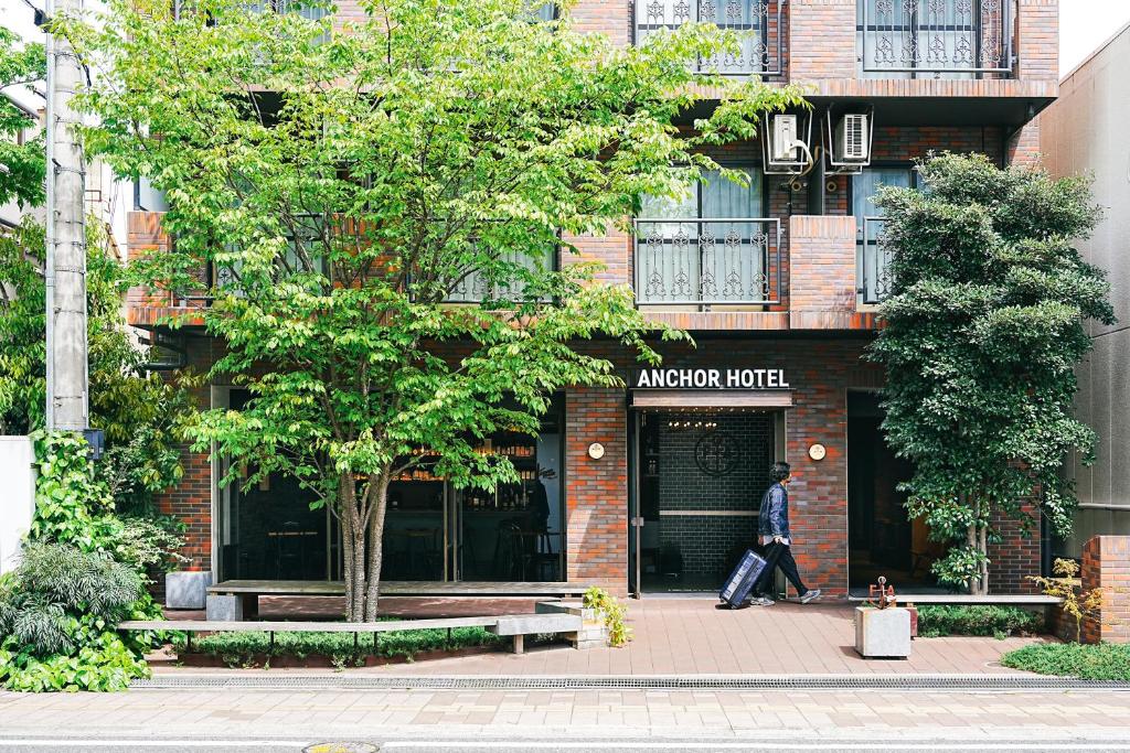 Anchor Hotel Fukuyama في فوكوياما: رجل يمشي أمام مبنى من الطوب