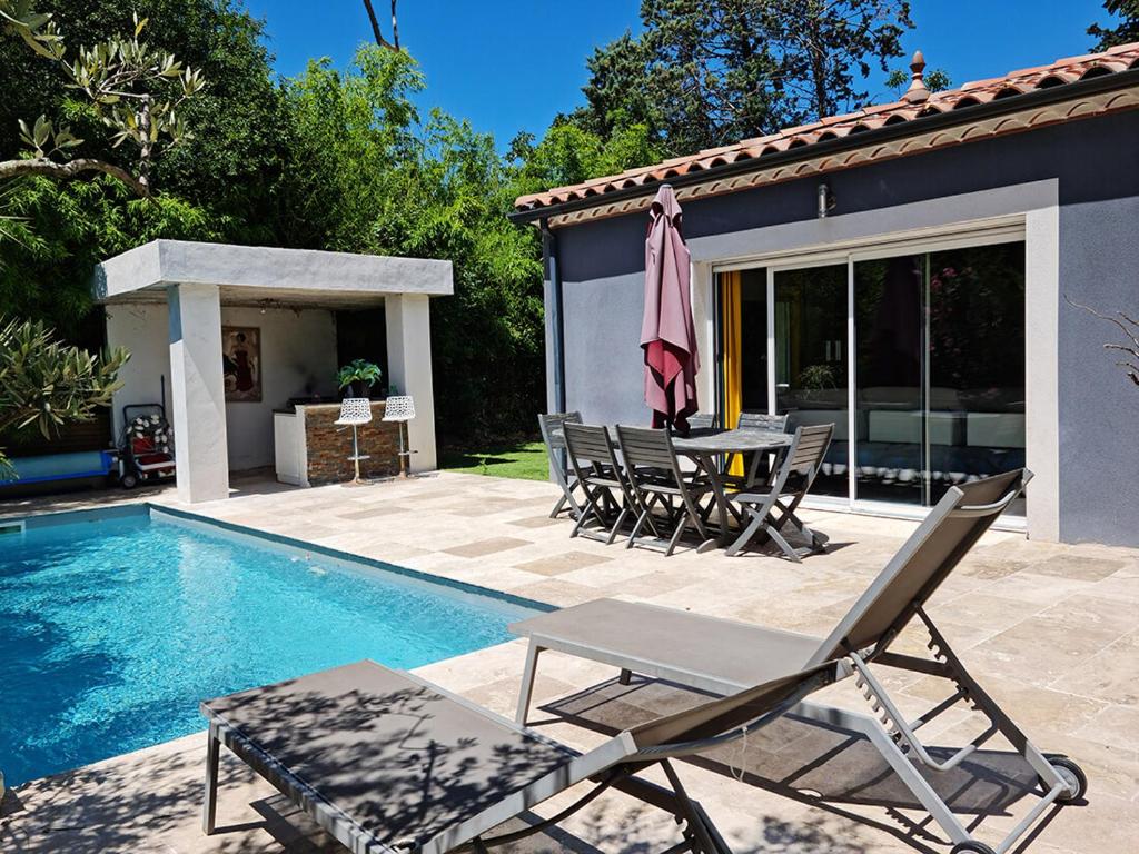 un patio con mesa y sillas junto a una piscina en Maison contemporaine aux portes des cevennes, en Alès