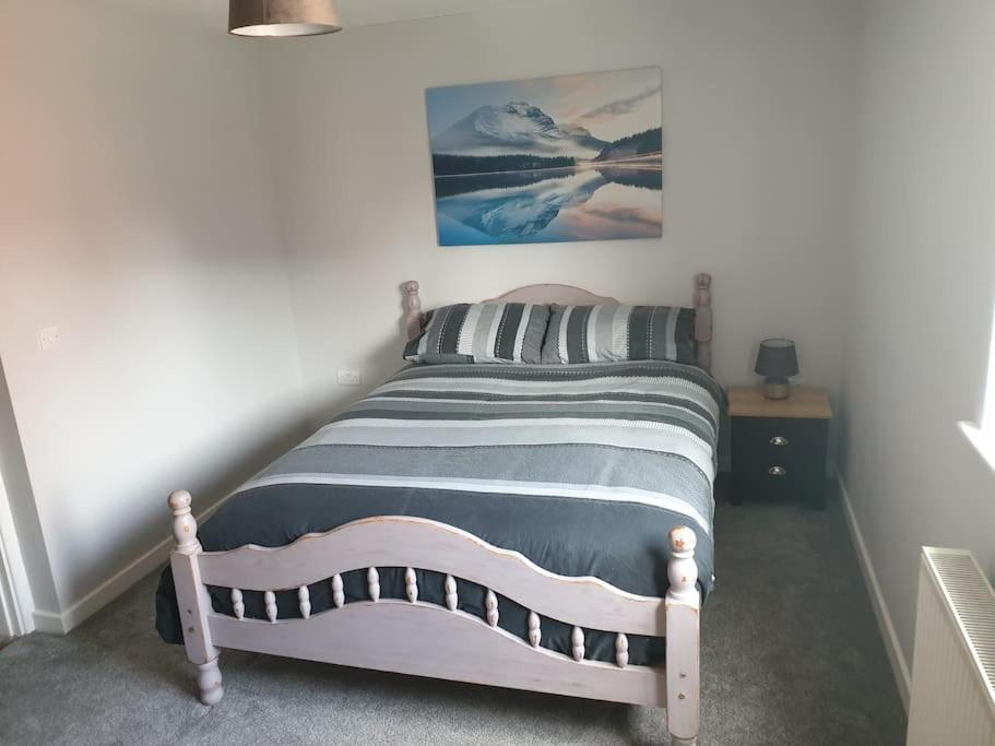 a bedroom with a bed with a picture on the wall at Ty Fi in Menai Bridge