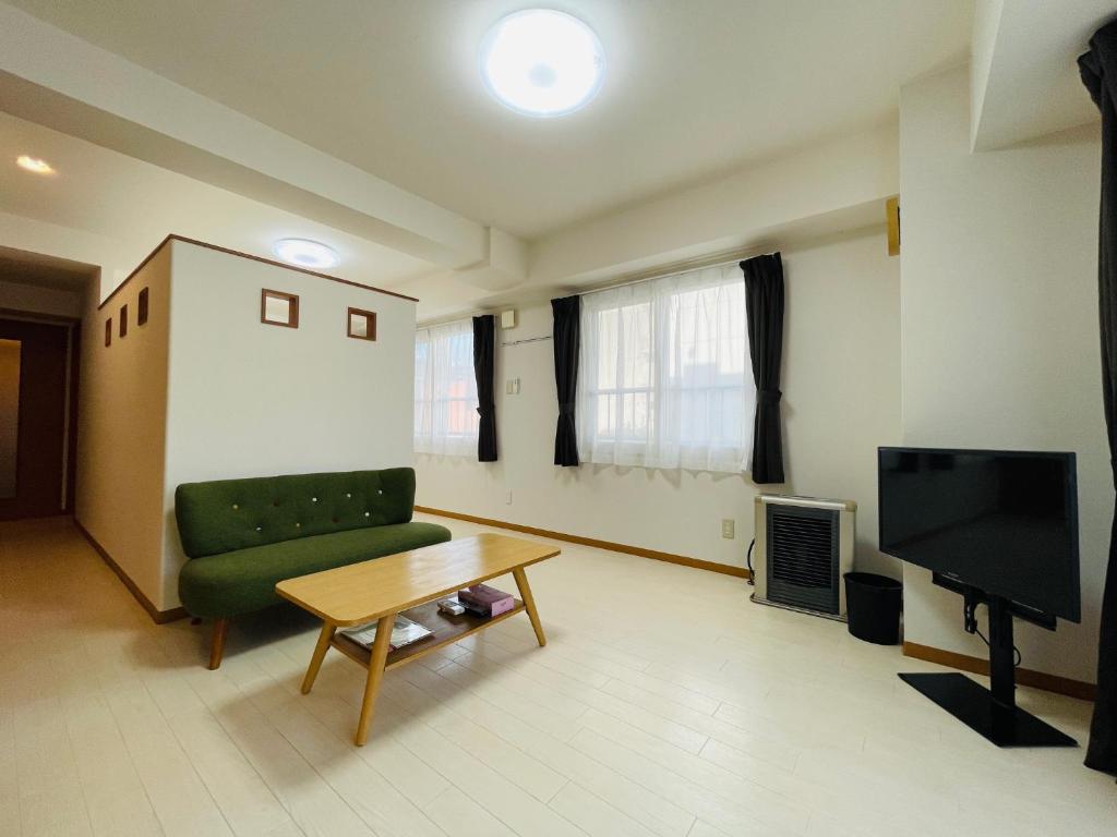 uma sala de estar com um sofá verde e uma televisão em 5-1観光スポット【大通公園】徒歩1分のサービスアパートメントSAPPORO大通西 em Ōdōri