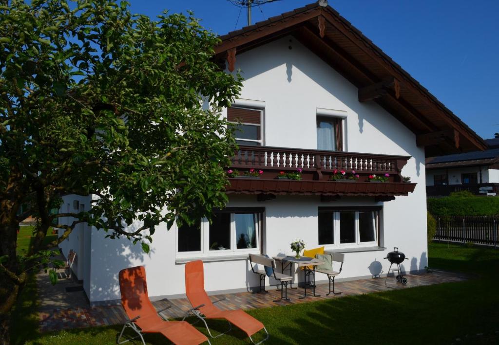 uma casa branca com uma varanda, uma mesa e cadeiras em Ferienhaus Antdorfer Gartenglück em Antdorf